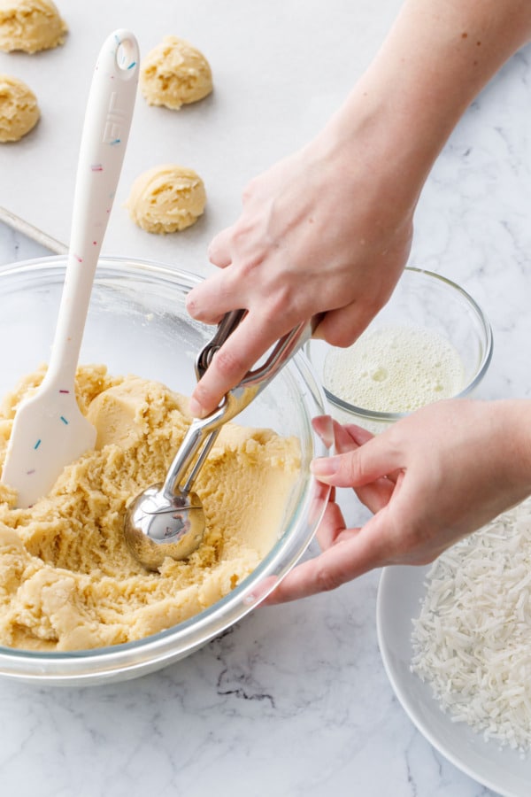 Using a cookie scoop to scoop balls of sugar cookie dough.