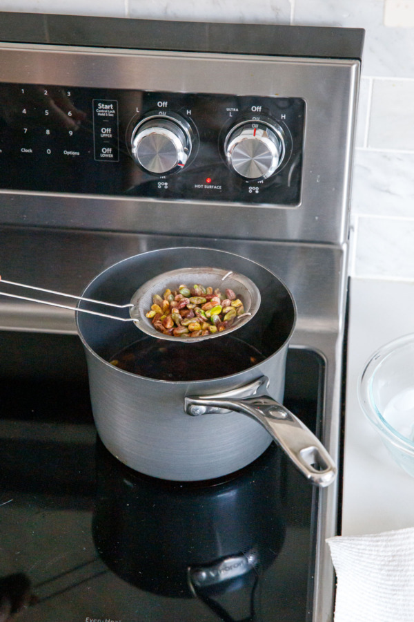 Using a spider/strainer to drain the pistachios after boiling for 30 seconds.