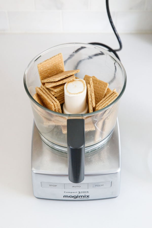 Whole squares of graham crackers in a food processor before grinding.