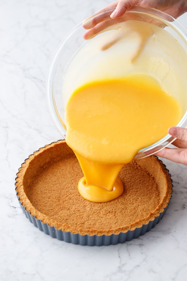 Pouring the Mango Lime Tart filling mixture into the par-baked graham cracker crust.