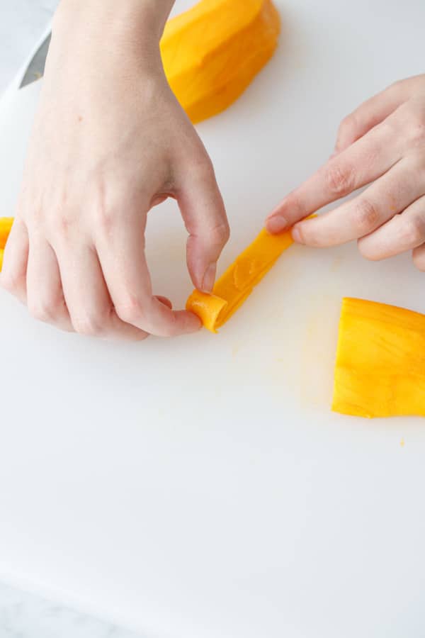Gently roll up the sliced mango to form a roll shape.