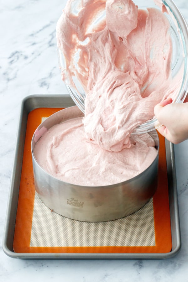 Pouring raspberry mousse to fill up the rest of the cake ring.