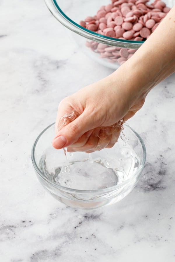 Squeezing softened leaf gelatin in a fist to remove excess water.