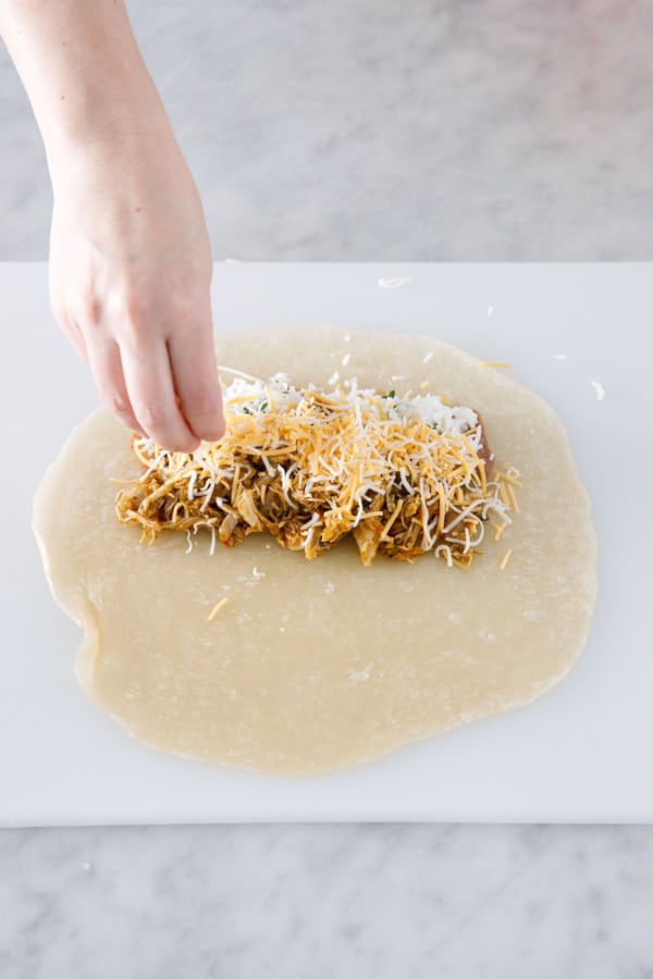 Sprinkling filling mixture with shredded Mexican cheese.