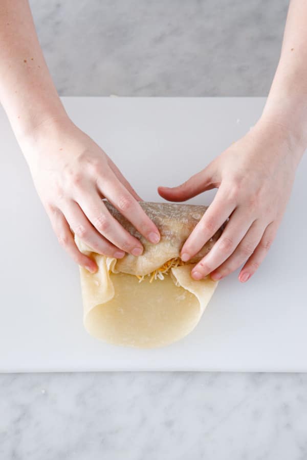 Rolling up the Crispy Chicken, Rice, & Bean Burritos in flour tortillas.