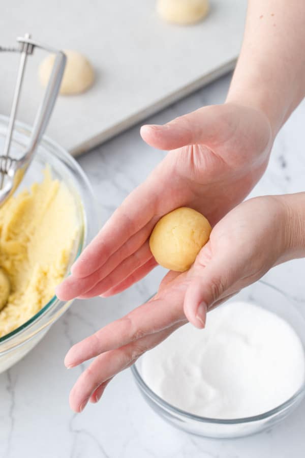 Rolling the ball of dough between your palms to form a smooth round ball.