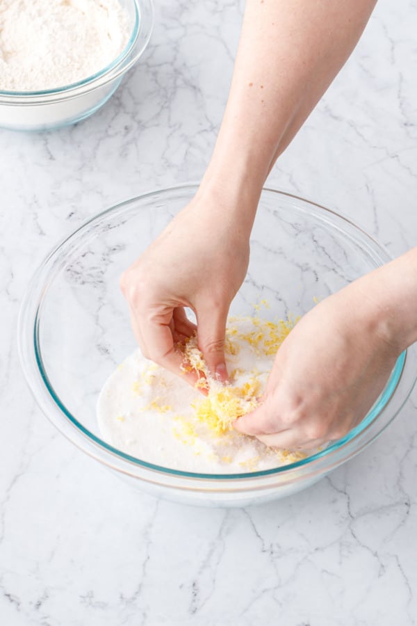 Hands rubbing the lemon zest into the sugar to help release the flavors.