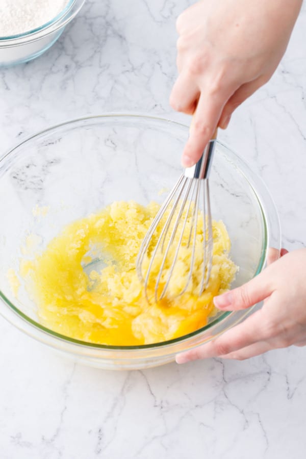 Whisking eggs into batter in a glass mixing bowl.