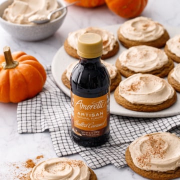 Plate with Caramel Pumpkin Cookies with Salted Caramel Frosting, bottle of Amoretti Salted Caramel flavoring in the foreground.