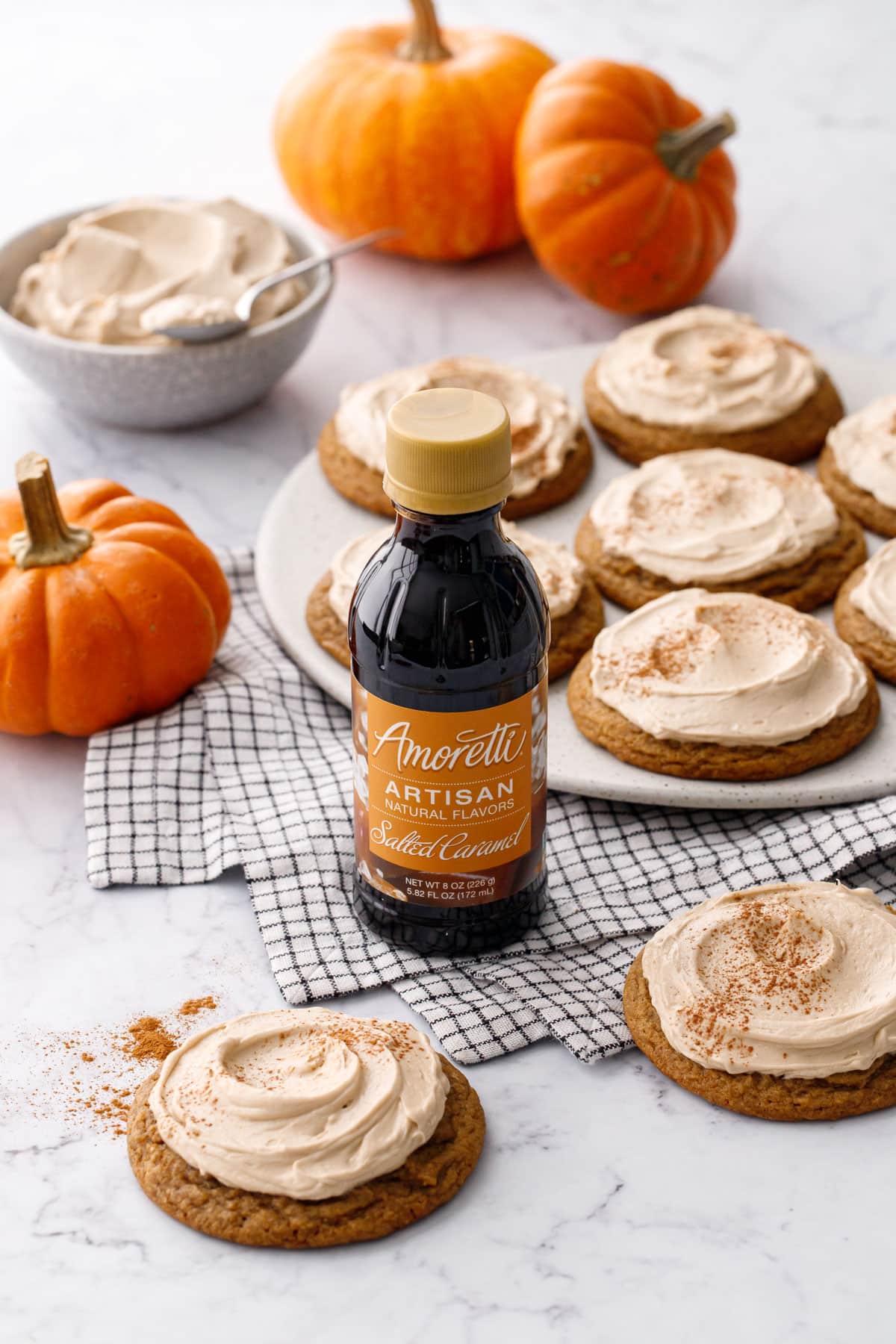 Plate with Caramel Pumpkin Cookies with Salted Caramel Frosting, bottle of Amoretti Salted Caramel flavoring in the foreground.