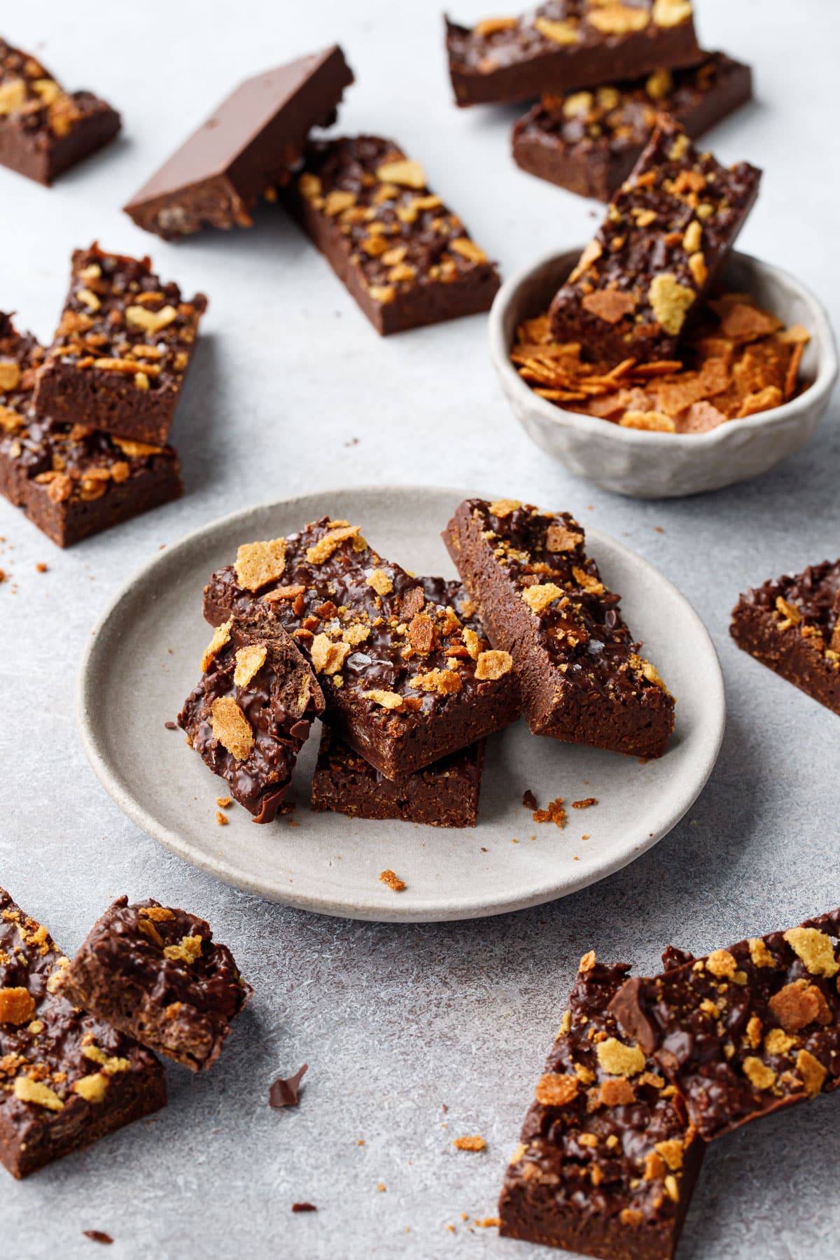 Bars of Nutella Chocolate Crunch Candy Bark scattered on a gray background, three bars stacked on a plate with one broken bar to show the crispy texture.