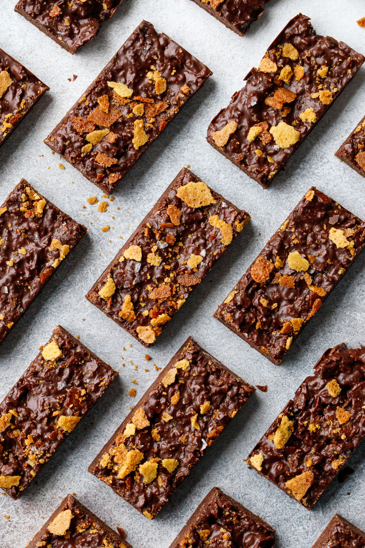 Overhead view, Rectangular cut Nutella Chocolate Crunch Candy Bark arranged diagonally in rows on a gray background.