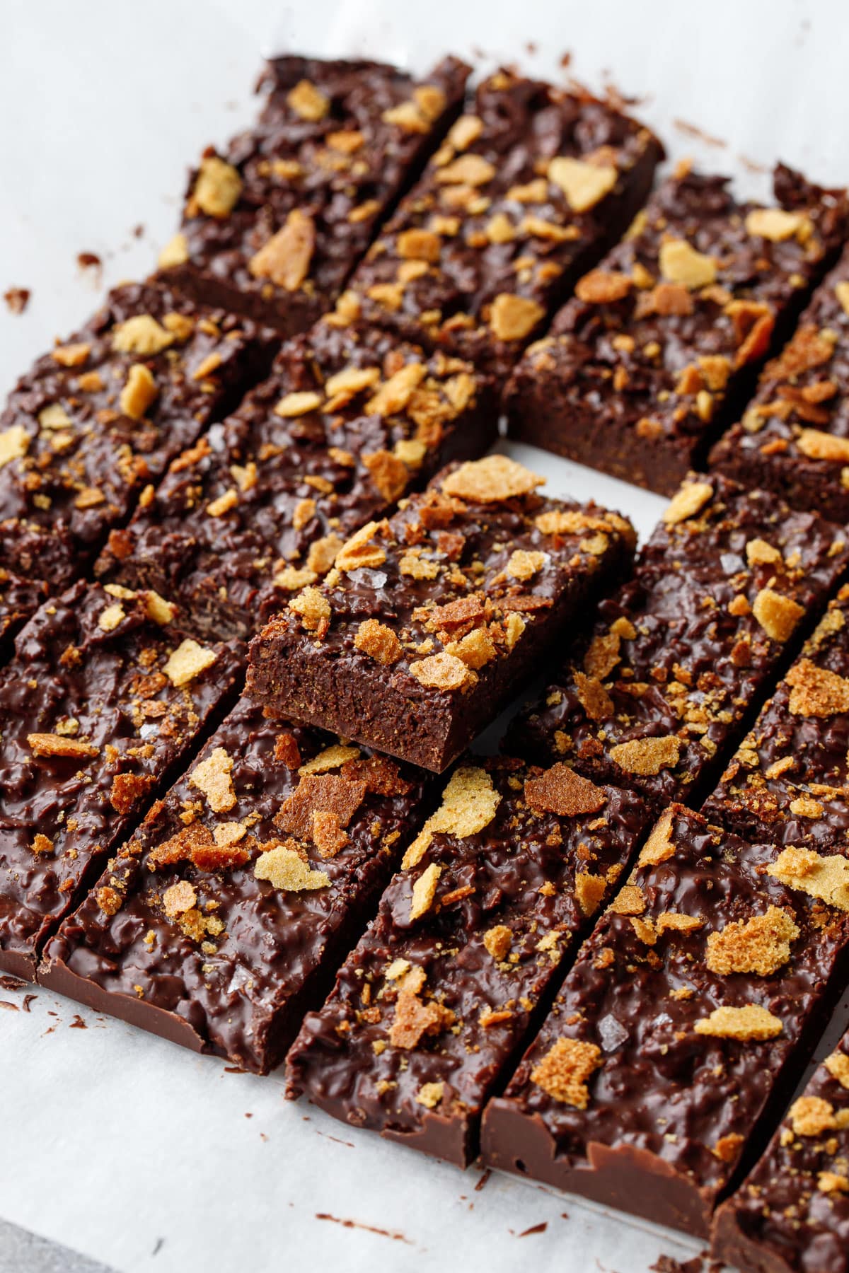 Freshly cut bars of Nutella Chocolate Crunch Candy Bark on parchment paper, one bar propped up to show the cross section of texture.