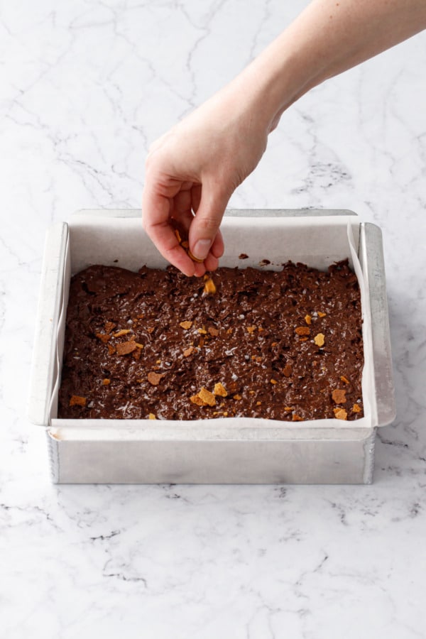 Sprinkling top of assembled candy bark with crushed feuilletine flakes.