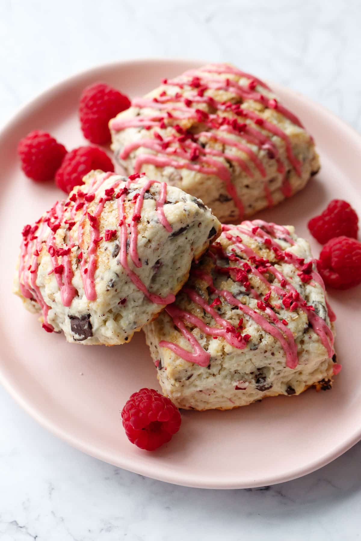 Pink plate with 3 square Dark Chocolate Raspberry Cream Scones and a few fresh raspberries.