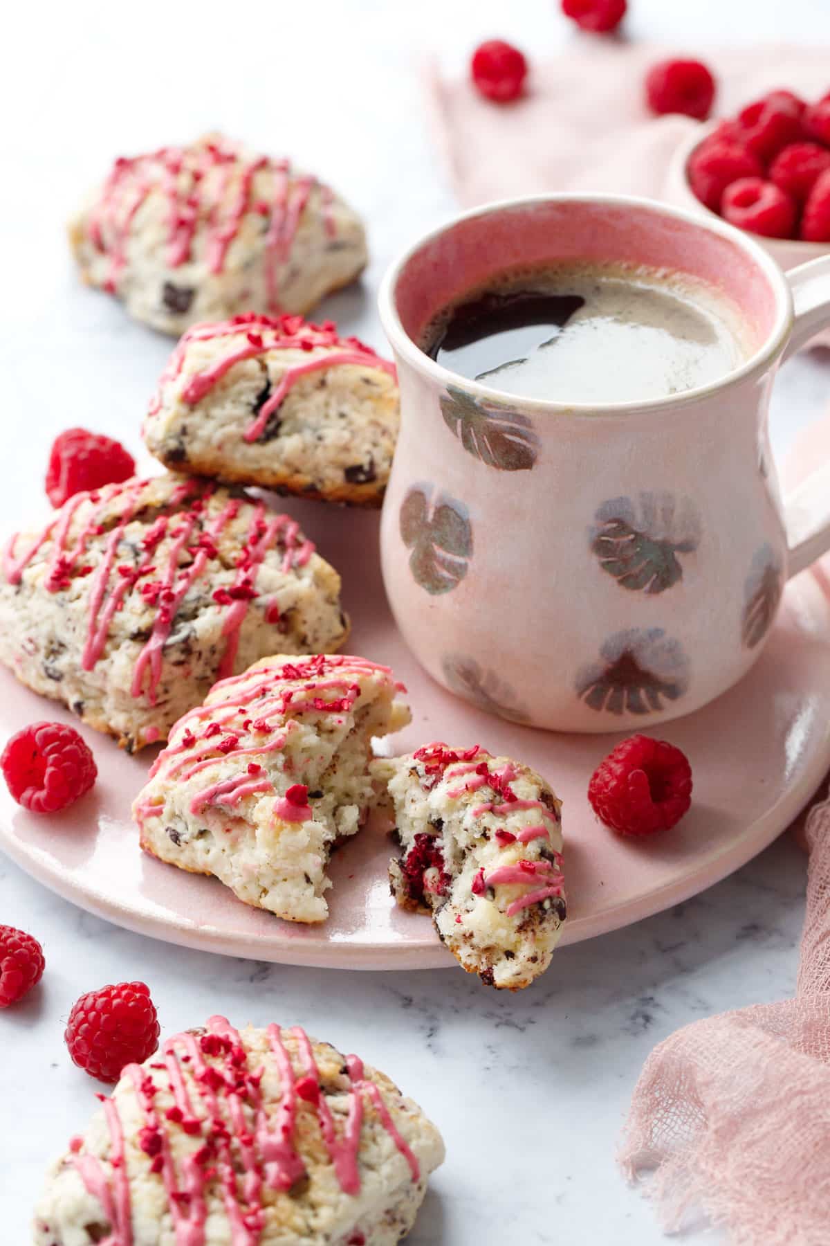 Pink serving plate with Dark Chocolate Raspberry Cream Scones and a homemade ceramic mug filled with coffee.