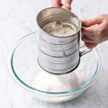 Sifting flour into a glass mixing bowl.