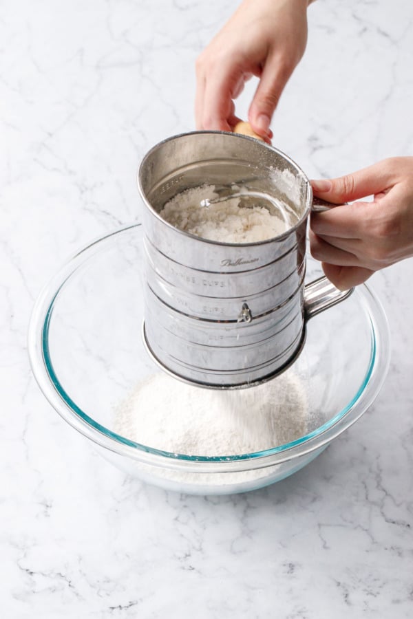 Sifting flour into a glass mixing bowl.