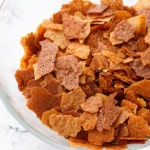 Bowl of Homemade Feuilletine Flakes on a white marble background.