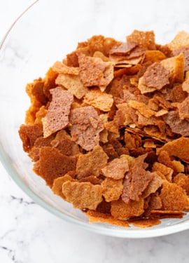 Bowl of Homemade Feuilletine Flakes on a white marble background.