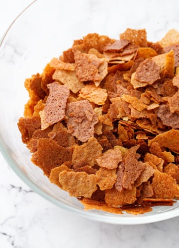 Bowl of Homemade Feuilletine Flakes on a white marble background.