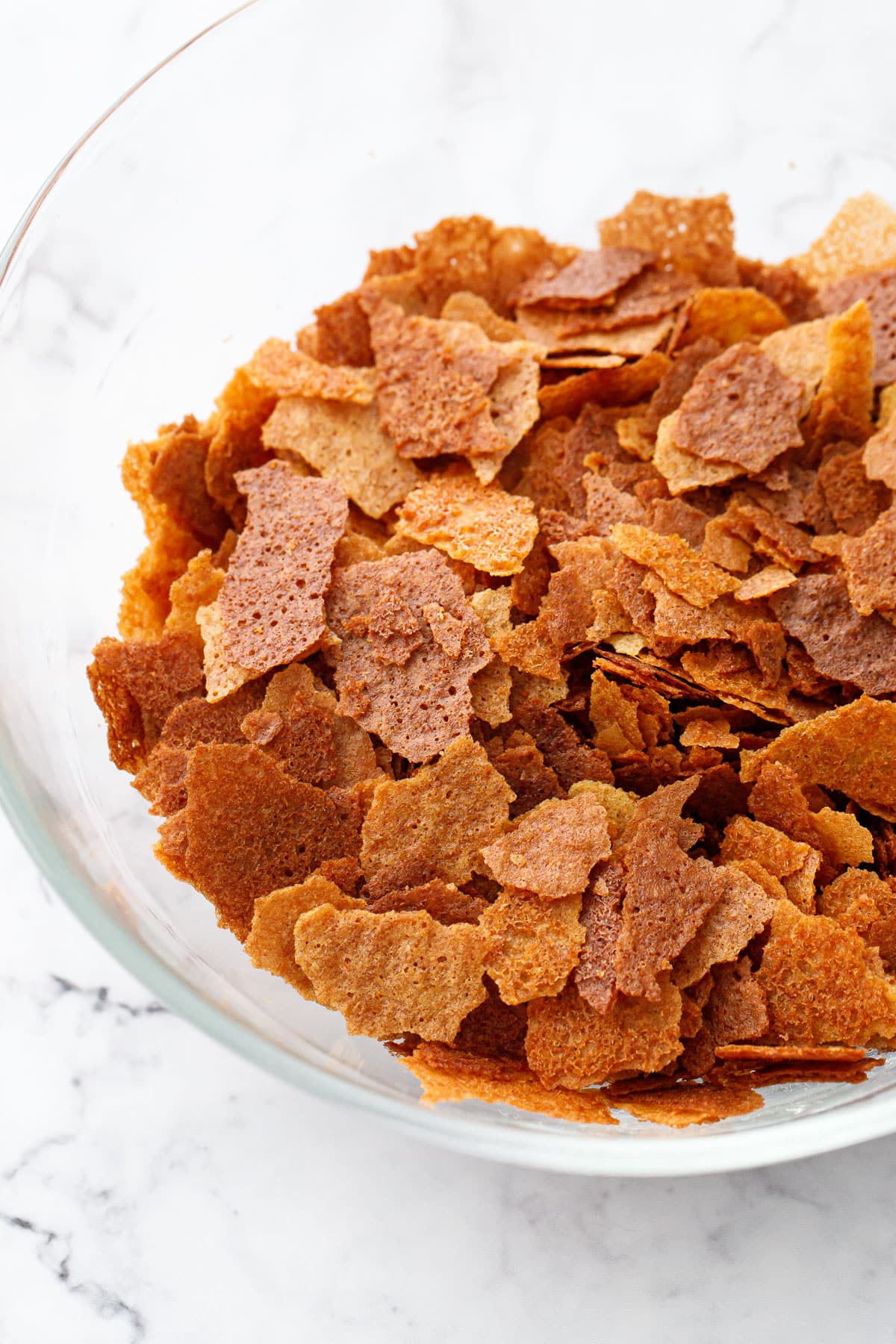 Bowl of Homemade Feuilletine Flakes on a white marble background.