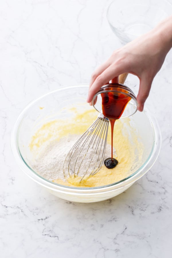 Pouring 2 teaspoons of molasses into glass mixing bowl with other ingredients.