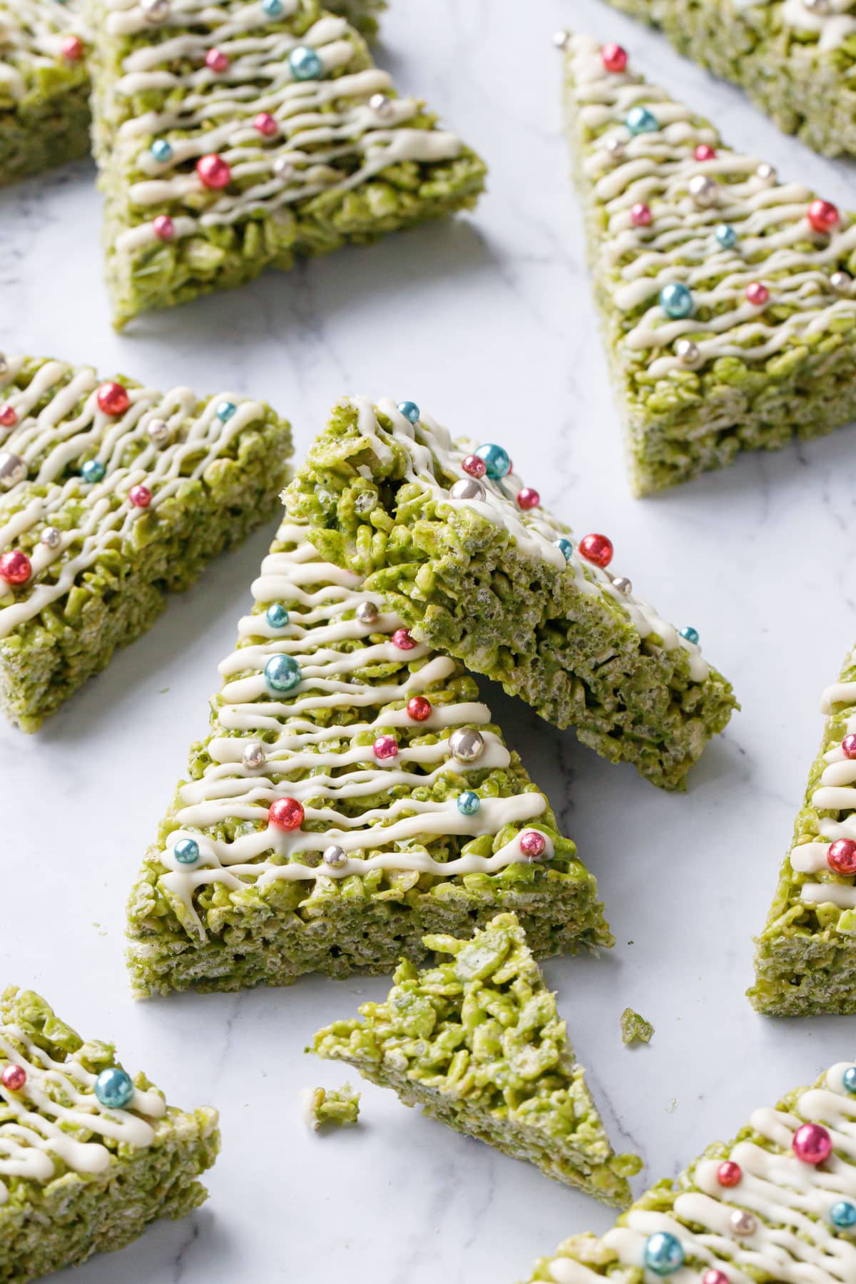 Matcha Rice Crispy Treats on a marble background, one with a bite out of it to show the interior texture.