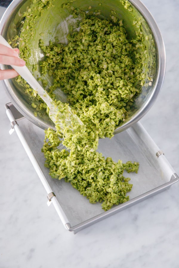 Pouring matcha rice crispy treat mixture into a parchment lined 13-by-9-inch baking pan.