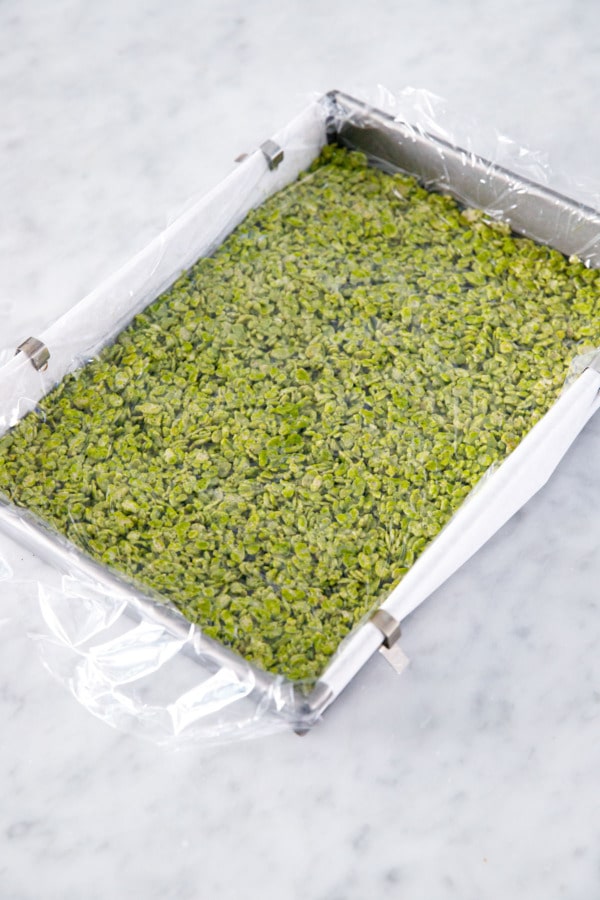 Baking pan with Matcha Rice Crispy Treats covered in plastic wrap.