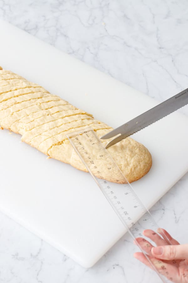 Using a clear ruler to mark off 1/2-inch wide pieces of biscotti.