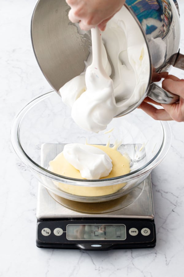 Using a kitchen scale to add whipped egg whites to bowl with cake batter.