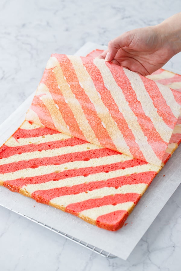 Peeling off the backing piece of parchment paper to reveal the baked stripes underneath.