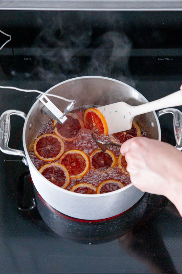 Using a fork and spatula to flip over the blood orange slices in the syrup.