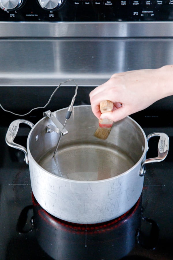 Brushing down the sides of the saucepan with water and a pastry brush.