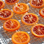 Homemade Candied Blood Orange Slices on a wire rack in bright direct light to showcase the stained-glass like appearance.