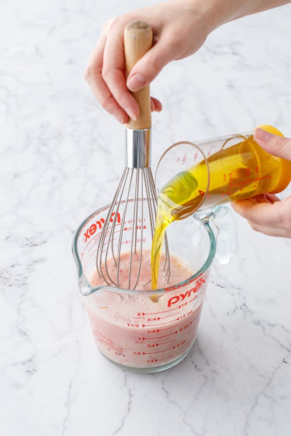 Pouring olive oil into measuring cup with other wet ingredients.