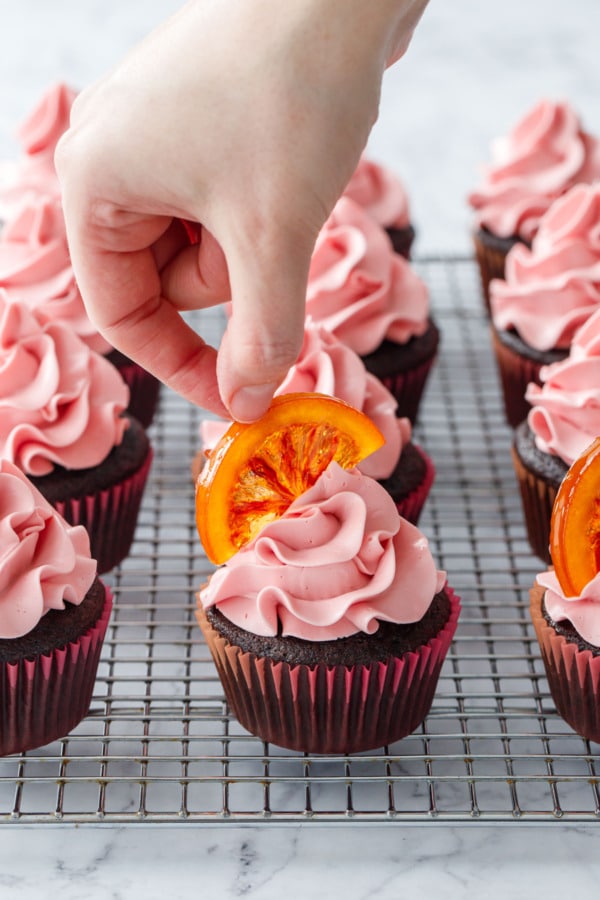 Topping frosted cupcakes with a half-moon slice of candied blood orange.