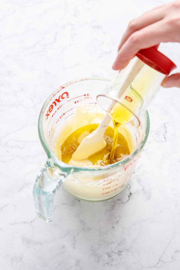 Pouring olive oil into measuring cup with partially melted butter.