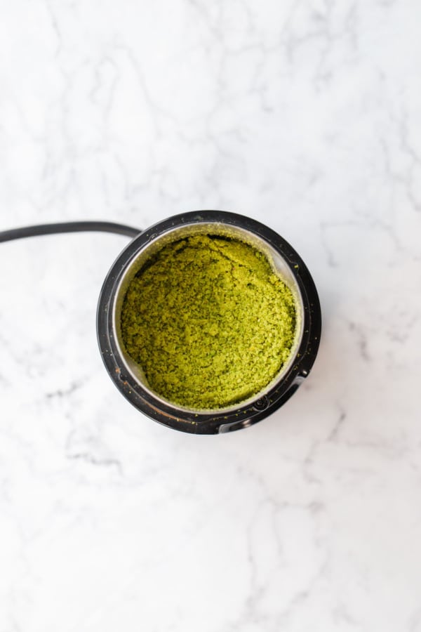 Overhead, looking into the canister of a coffee grinder after grinding pistachios into flour.