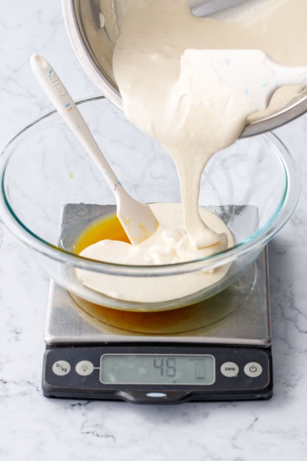 Pouring half of the cooked egg/sugar mixture to a glass mixing bowl with passionfruit base.