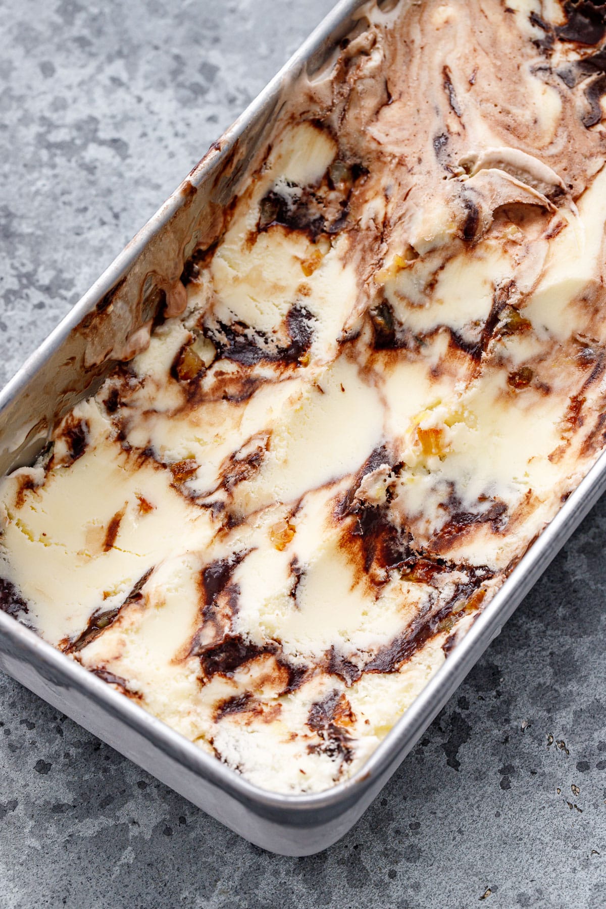 Loaf pan with Candied Orange Ice Cream, with a visible swirl of chocolate fudge and bits of candied orange throughout.