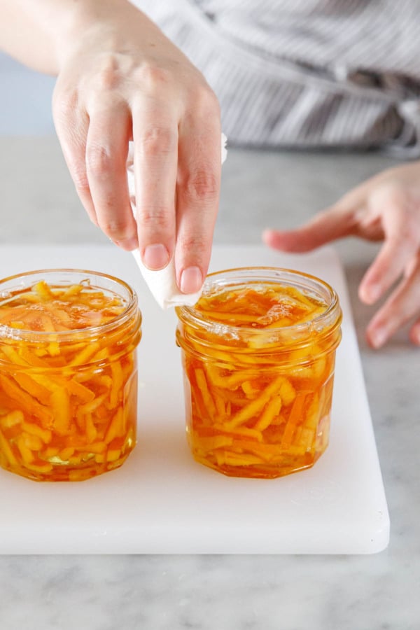 Using a damp paper towel to wipe off the rims of the jars.