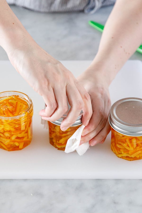 Tighten canning jar lids onto jars.