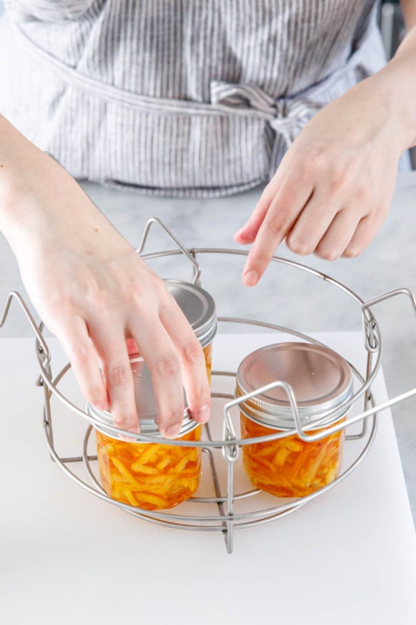 Transferring lidded jars into a canning rack.