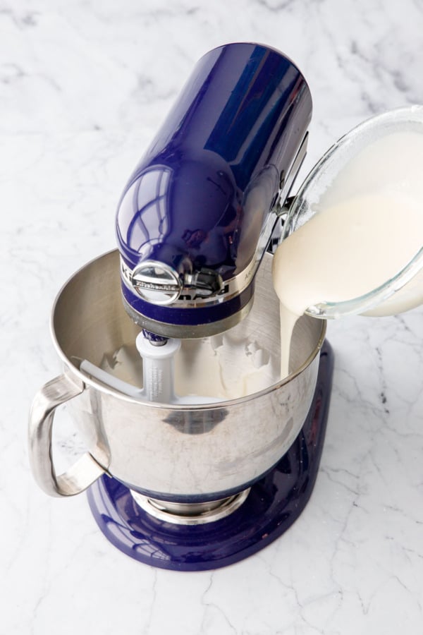 Pouring some of liquid sugar mixture into mixing bowl with well creamed butter.