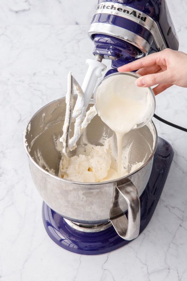 Pouring a bit of melted buttercream frosting back into mixing bowl with rest of buttercream.