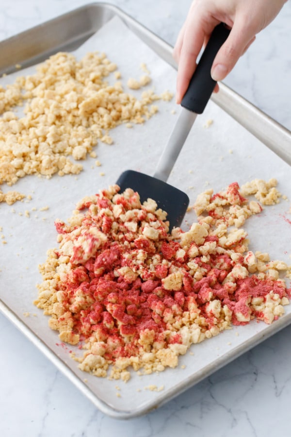 Tossing strawberry powder with a portion of the baked shortcake crumbs.