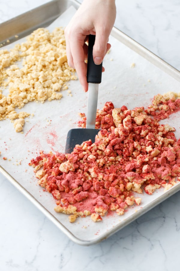 Tossing strawberry powder with a portion of the baked shortcake crumbs.