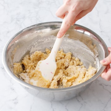 Stirring melted butter into dry ingredients with a silicone spatula.